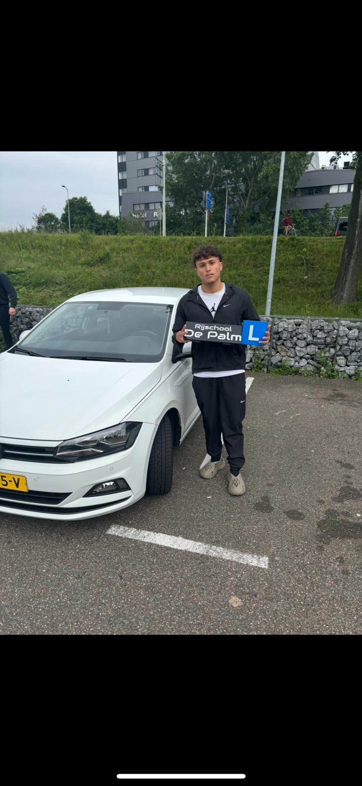 Geslaagde leerling met rijschoolauto